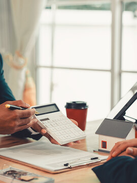 Real estate agent pointing at contract document on clipboard, explaining terms to client during home loan insurance meeting.