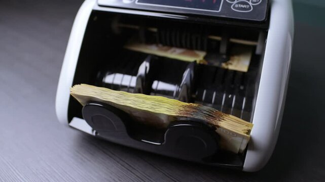 Counting Canadian Dollars With an Electronic Machine in Slow Motion