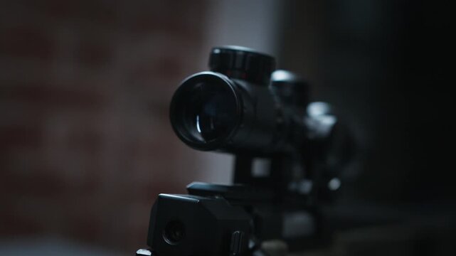 Cinematic close-up of a black rifle scope mounted on a mounted firearm against a soft blurred brick interior.