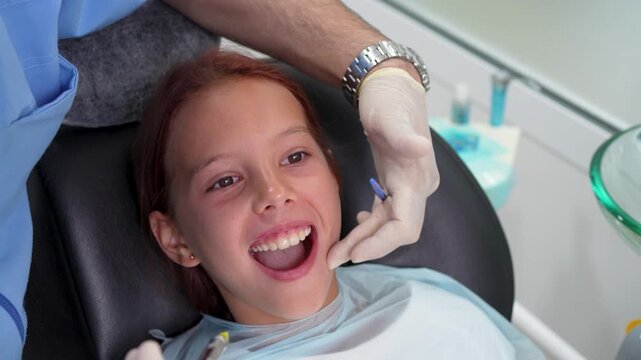 Dentist giving local anesthesia injection to little girl with dental carpule syringe close up.