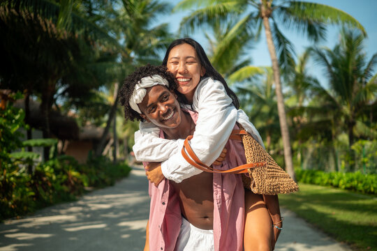 Happy young couple embracing and laughing on a tropical beach during summer vacation
