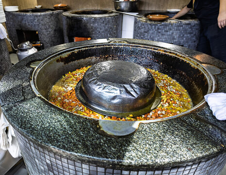 Professional Uzbek restaurant kitchen with multiple traditional cauldrons for simultaneous preparation of authentic dishes.