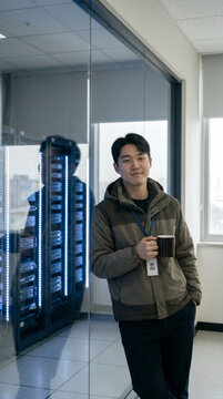 Young technician holding a coffee cup while standing in a data center server room