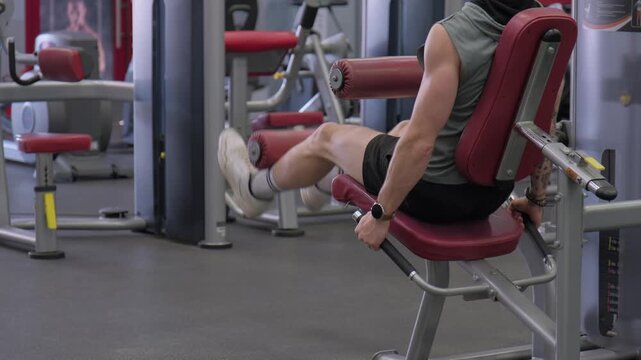 Man exercises legs using machine at gym in afternoon