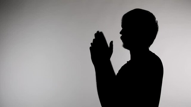 An anonymous silhouette of a man standing against a white background and clapping his hands
