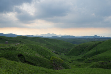 Fototapeta premium Sunset View of Orange Sky and Rolling Hills Along Aso Milk Road, Kumamoto, Japan