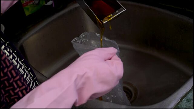 Gloved hand removing dirty cooker hood filter for cleaning or service. Grease and grime buildup requires regular maintenance for modern kitchen appliance hygiene.