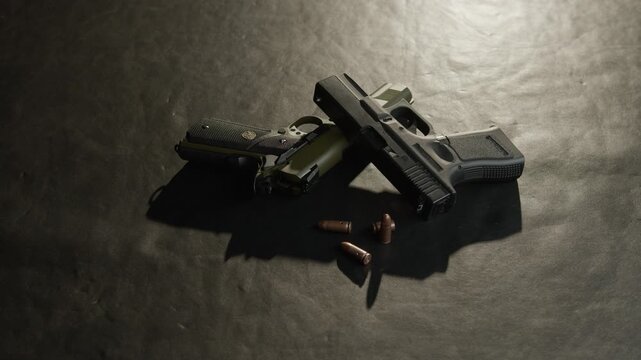 Close-up of modern pistols and scattered cartridges arranged on a textured tabletop in a cinematic studio scene.
