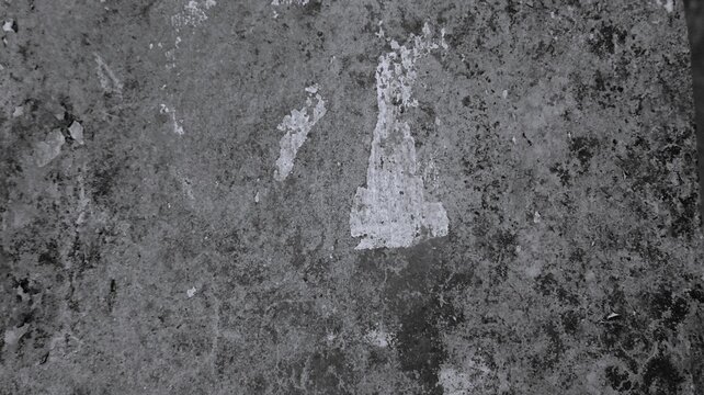 Black and white aged cement background with patchy stains, worn plaster traces, rough surface grain, and distressed urban texture.