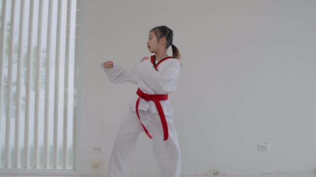 Young girl tying red belt in martial arts class at home during the day