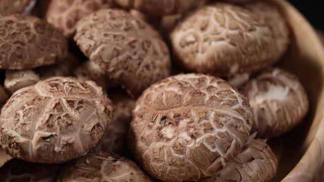 Close-up of fresh shiitake mushrooms arranged on a rustic wooden table. Natural edible mushrooms with rich texture and earthy flavor, widely used in Asian cuisine and healthy cooking. Ideal for themes