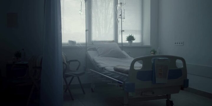 An unoccupied hospital room with a medical bed and an IV stand presents a somber atmosphere, suggesting a place of healing and quiet recovery during a challenging time for patients seeking