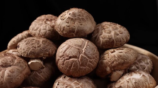 Close-up of fresh shiitake mushrooms arranged on a rustic wooden table. Natural edible mushrooms with rich texture and earthy flavor, widely used in Asian cuisine and healthy cooking. Ideal for themes