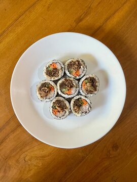 Korean Bulgogi Kimbap Rice Rolls with Beef Carrot and Vegetables on White Plate for Asian Cuisine and Korean Food Background