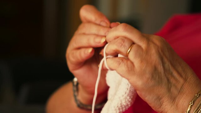 Mature woman crocheting white yarn.