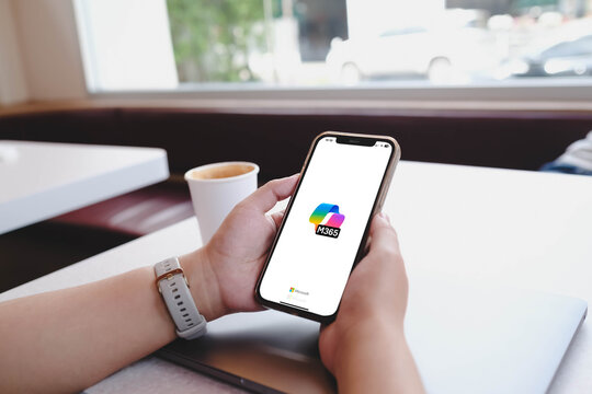 Bangkok, Thailand. June 27, 2026; A person holding a smartphone displays the Microsoft 365 application logo while sitting at a table with a coffee cup.