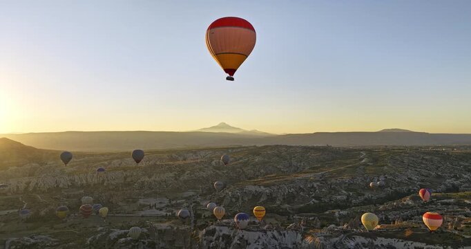 G�reme Turkey Aerial v60 cinematic flying up high over the town and around hot air balloon capturing beautiful golden sunrise landscape of volcanic rock formations - Shot with Mavic 3 Cine - July 2022