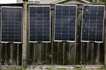 Plastic solar panels on the fence of a house as a DYI system © Ivelin
