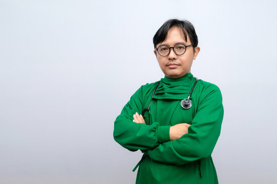 A man with glasses wearing a green long-sleeved surgical gown carrying a stethoscope isolated on white background