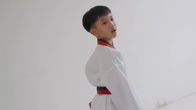 Young boy practices martial arts moves in a training studio near noon in warm weather