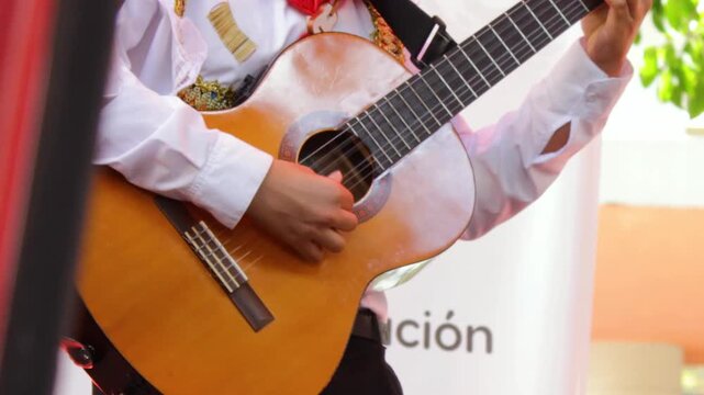 An unrecognizable man in traditional clothing plays an acoustic guitar during a live show at the San Juan and San Pedro Festival in Neiva, Huila, Colombia. Concept of Colombian music