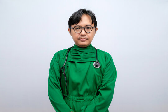 A man with glasses wearing a green long-sleeved surgical gown carrying a stethoscope isolated on white background