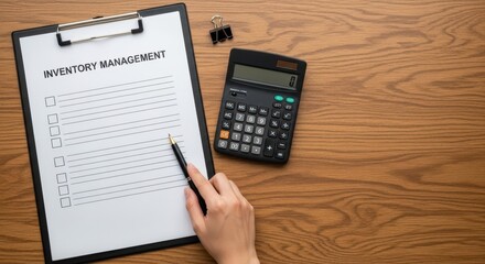 Obraz premium Hand reviewing a management checklist document with a pen next to a calculator and binder clip on a wooden desk.