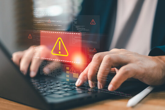 Programmer typing on laptop with virtual warning triangle icon alert for system error, software bug, cyber attack hack, server downside, data breach and digital security threat concept