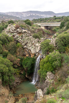 The Saar Falls in the Winter with people reppalling and the bridge above in the Golan Heights in northern Israel.
