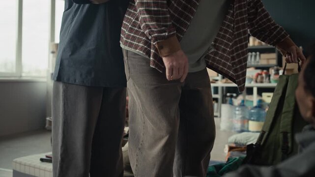 Senior Caucasian man sitting down in temporary humanitarian aid shelter and talking to Black man. Ideal for social advocacy campaigns, charity promotions, and documentary storytelling