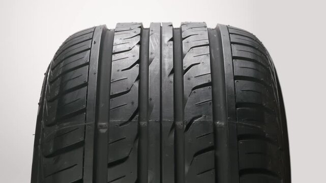 Demonstration of a New Car Tire. New car wheel close-up slowly spinning showing tread pattern on white background