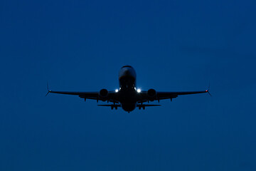 Commercial Passenger Airplane Landing at Dusk with Landing Lights On   Lądowanie komercyjnego samolotu pasażerskiego o zmierzchu z włączonymi światłami lądowania © Adrian White