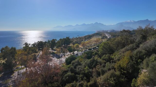 Aerial view of antalya coastline park and beach with taurus mountains and glittering sea.