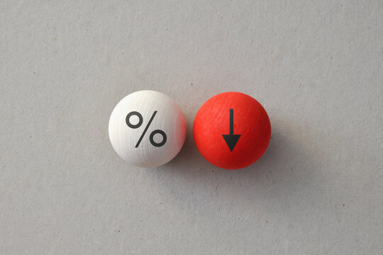 Interest rate decrease concept with percent symbol and downward arrow on wooden balls