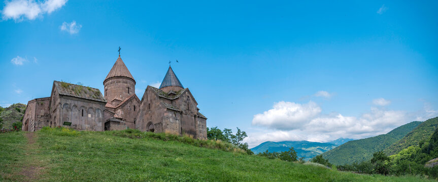 Wide panorama of Goshavank monastery in mountains under blue sky with copy space