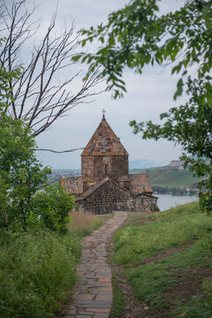 Vertical Sevanavank monastery path framed by green leaves with copy space