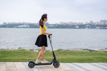 Side view woman riding electric scooter © leungchopan