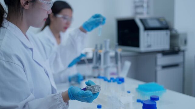 Female scientists conducting experiment with micropipette and test tubes in a modern scientific research laboratory