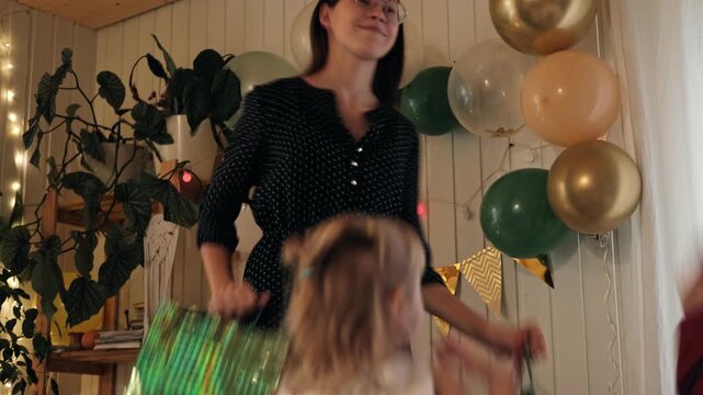Happy teenage girl celebrating birthday with jumping siblings at home party. Cheerful 14-years-old teen with little brother and sister dancing in festive room. Authentic Dynamic Motion. Gen Z Parties
