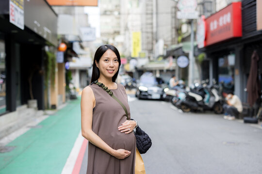 Happy pregnant woman walking outside
