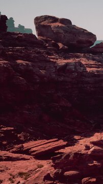A natural landscape features large rock formations and brown soil in clear weather. The scene shows rugged textures and shapes of the rocks under sunlight.