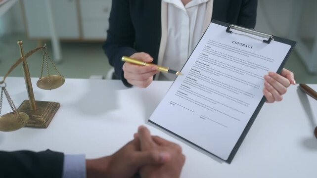 Lawyer explaining contract terms and pointing at the signature line with a pen to a male client in the office