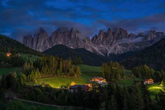 Night view of the Odle Mountains in the Dolomites with illuminated mountain chalets