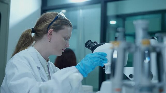Female scientist working in a laboratory analyzing samples with a microscope for medical research and development