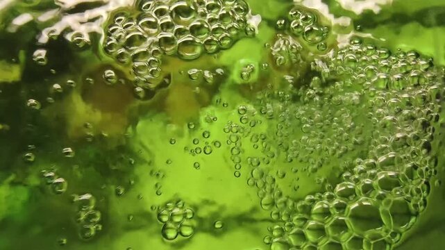Bubbling green liquid close up in a bioreactor