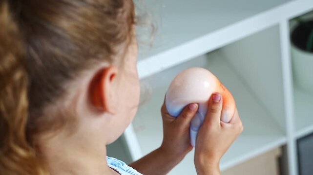 Child squeezes a soft squishy stress relief toy at home. Sensory play supports emotional regulation, relaxation and focus through tactile interaction.