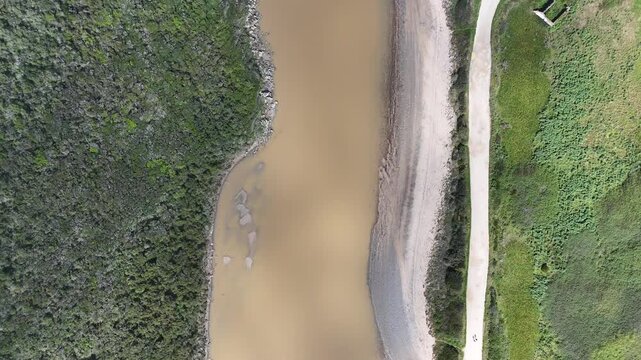 Aerial push in shot along the scenic Fisherman's Trail (Rota Vicentina) in Portugal, revealing a winding river and lush, remote landscape.