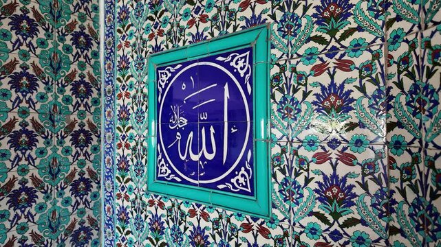 Islamic art background featuring Arabic calligraphy of Allah name on blue tile plaque surrounded by traditional Iznik floral patterns on mosque wall