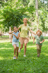 Fototapeta premium Joyful moments at the playground with mother and children in a sunny green setting