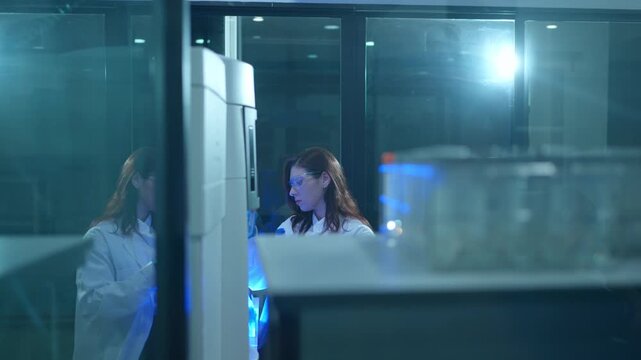 Female scientist working with a colleague in a high tech laboratory conducting biomedical research and experiments